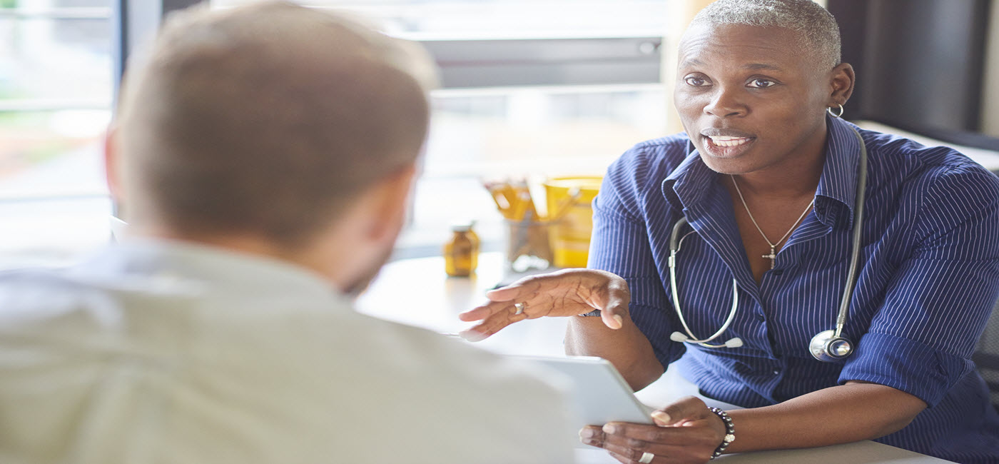 A physician discusses a patient’s case with medical students, while patient sits up in a hospital bed.!''